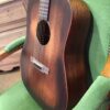 profil guitare acoustique posée sur fauteuil vert