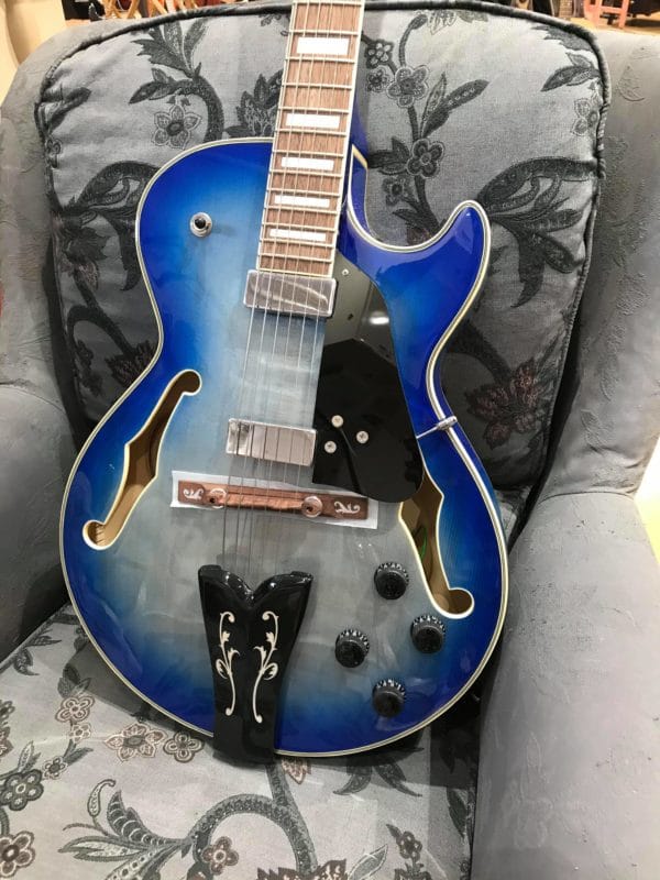 guitare bleue électrique posée sur fauteuil gris