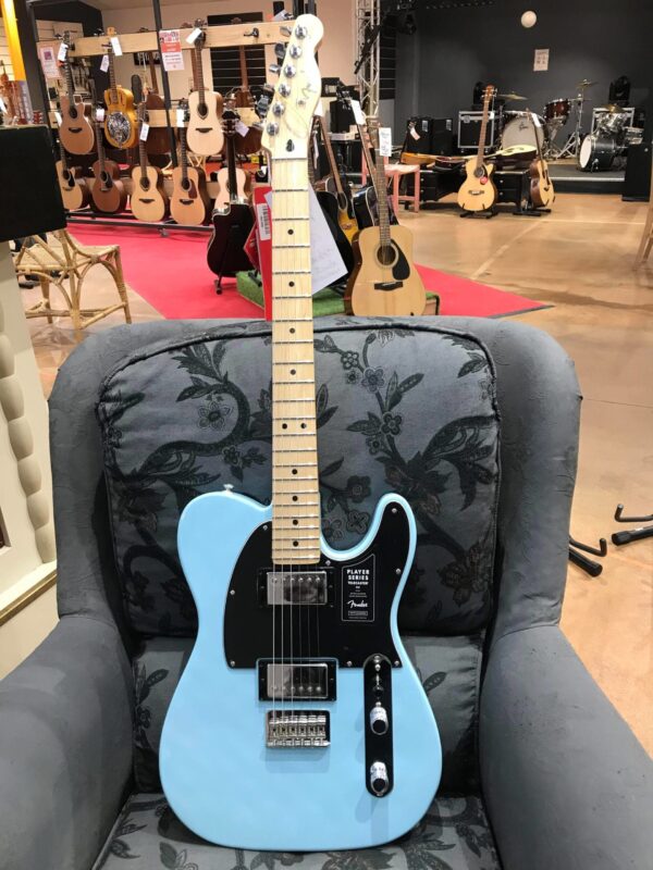 guitare électrique bleu posée sur fauteuil