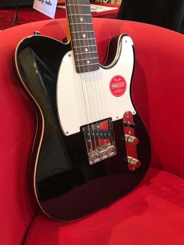 guitare électrique noire et blanche sur un fauteuil rouge
