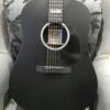 guitare acoustique noire posée sur fauteuil