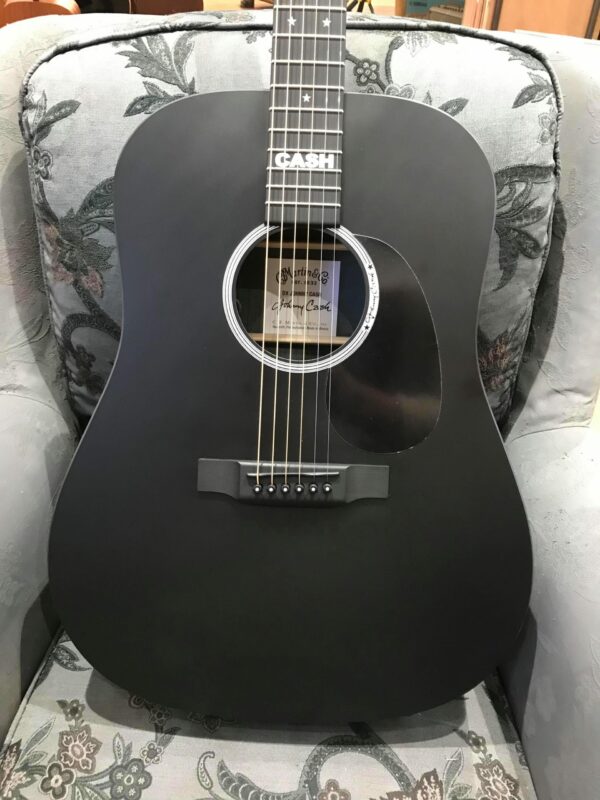 guitare acoustique noire posée sur fauteuil