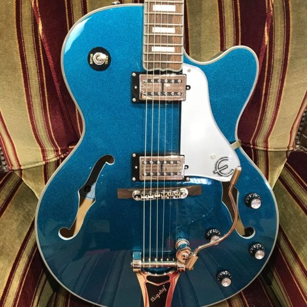 guitare électrique bleue paillette posée sur canapé