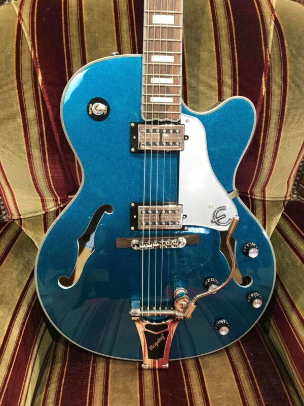 guitare électrique bleue paillette posée sur canapé